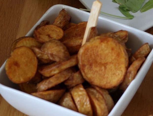 Weiße Schale mit grob geschnittenen, goldbraun gebratenen Kartoffelscheiben.