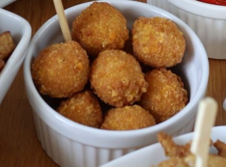 Weißes Förmchen gefüllt mit runden, goldbraun panierten Kroketten.